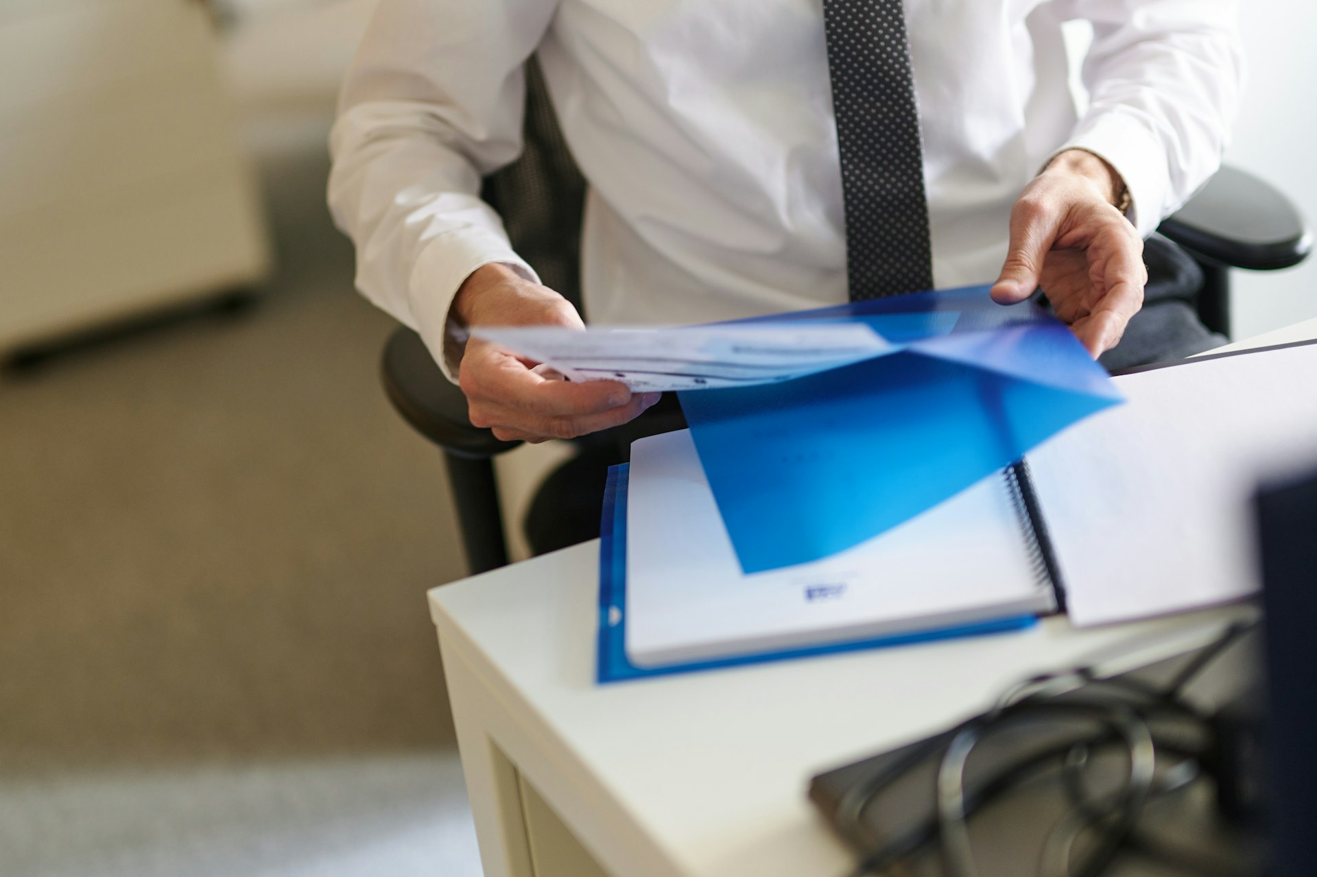 a man in a white shirt and tie holding a folder